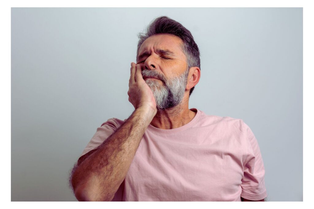 Man grabbing his jaw and grimacing from a toothache.